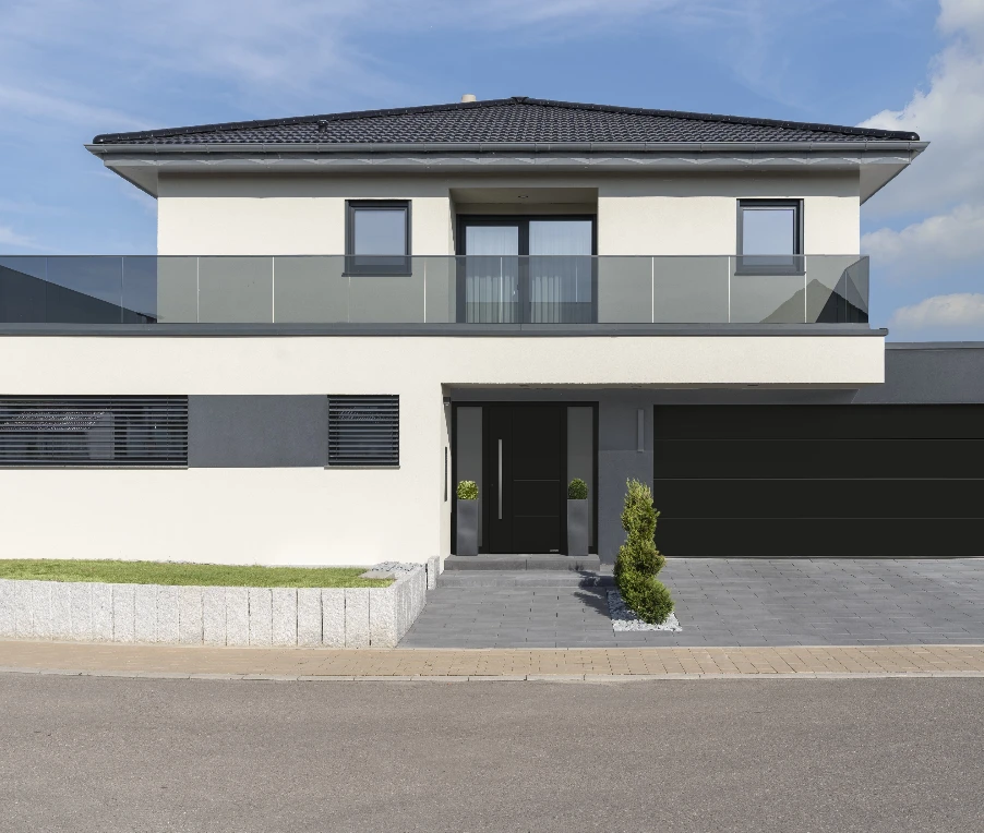 Modernes Wohnhaus mit Aluminium-Haustür, Garagentor und Balkon mit Glasgeländer