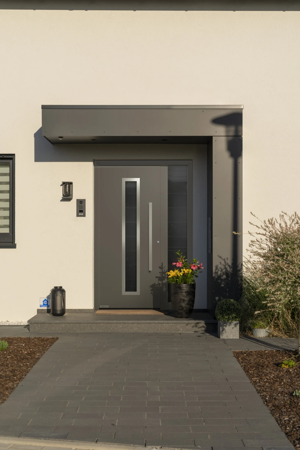 Moderne graue Aluminium-Haustür mit schmalem Glaseinsatz und langem Edelstahlgriff